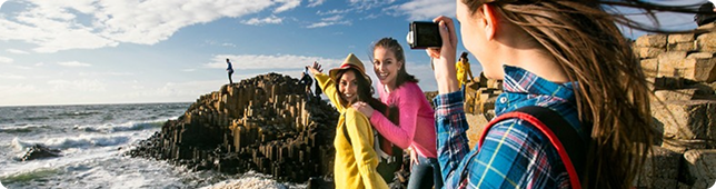 A group of women taking photos with the Giant’s Causeway in the background.