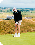 Man putting a golf ball on the green at an Irish golf course.