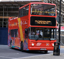 Open-top sightseeing bus touring Dublin city with passengers enjoying the view.